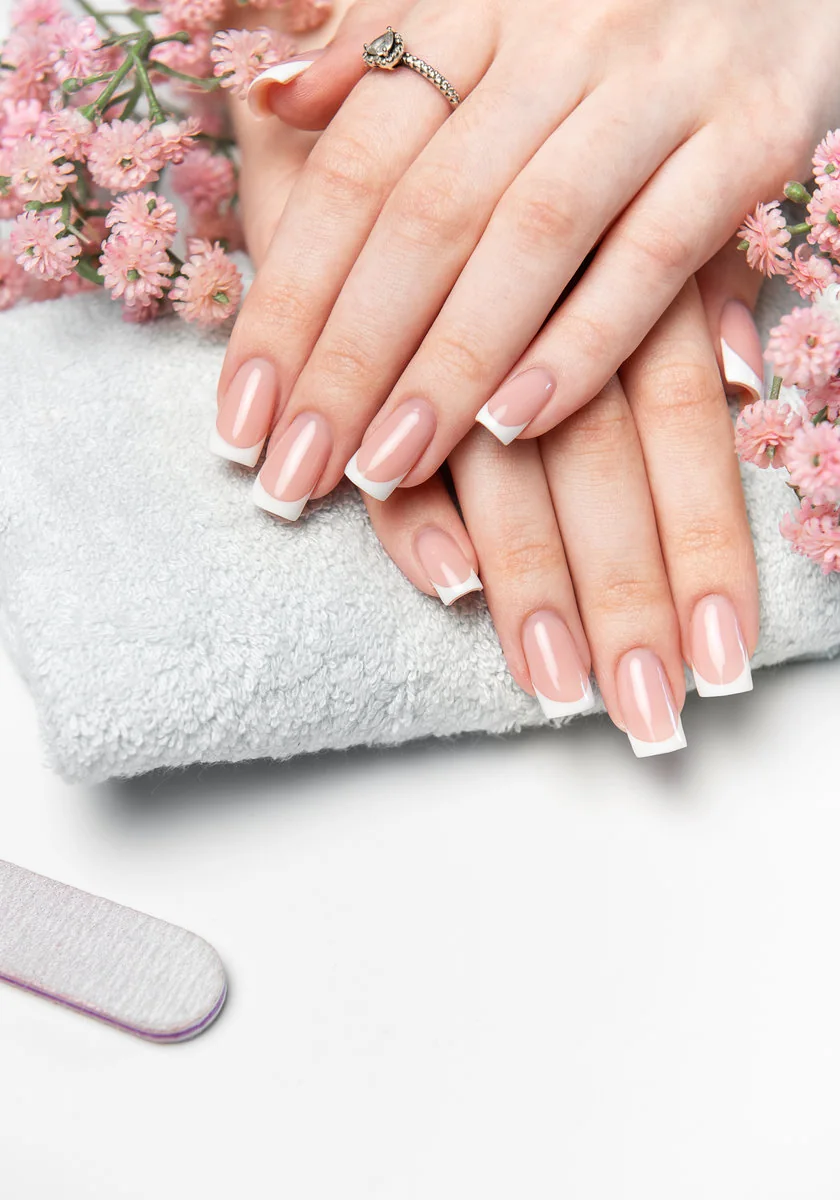 Manos con manicure francesa sobre una toalla blanca