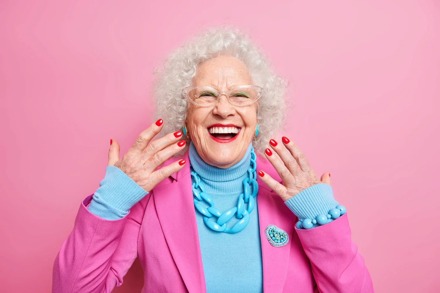 Mujer mayor sonriente mostrando su manicure rojo