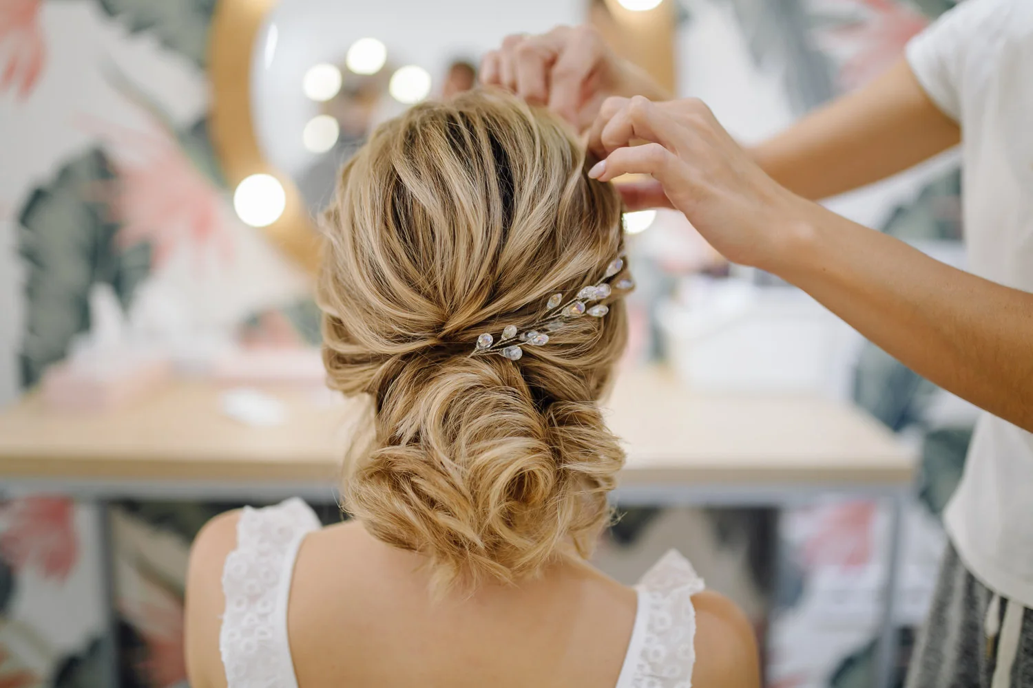 Profesional ajustando un peinado recogido de novia con accesorio