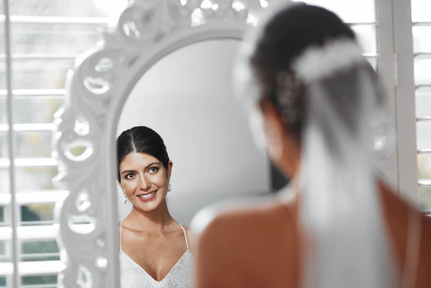 Novia observando su maquillaje frente a un espejo iluminado